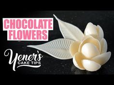 a white flower sitting on top of a table next to a black background with the words chocolate flowers