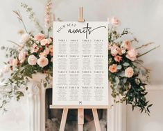 an easel with seating cards on it in front of a fireplace and floral arrangements