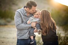 a man and woman holding a baby in their arms