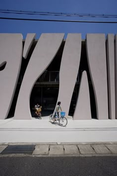 two people riding bikes in front of a large building with the word museum written on it