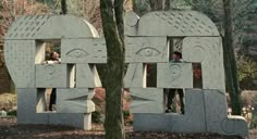 two stone sculptures in the shape of faces are shown next to each other near trees