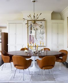 a dining room table with chairs and a chandelier hanging from the ceiling above it