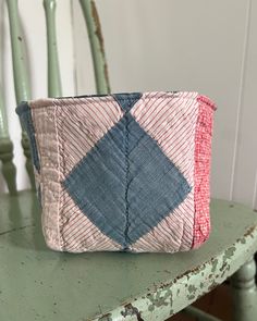 a blue and pink bag sitting on top of a green table next to a chair