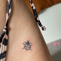 a lady bug tattoo on the back of a woman's thigh