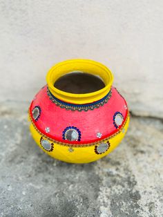 a yellow and red vase sitting on top of a cement floor