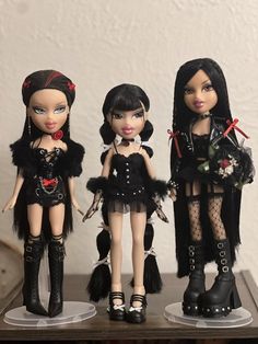 three dolls are dressed in black clothing and boots