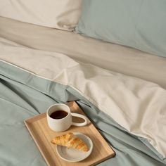 coffee and croissants are on a tray on the edge of a bed