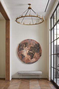 a room with a bench, chandelier and large round painting on the wall