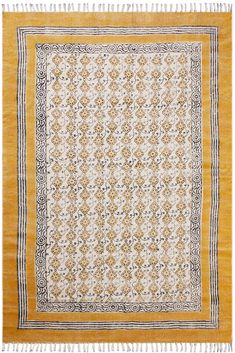 a yellow and white rug with fringes on the bottom, in an ornate pattern