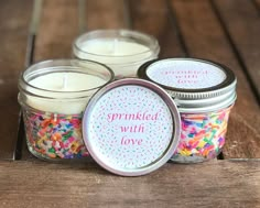 three jars filled with colorful sprinkles sitting on top of a wooden table