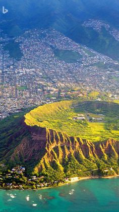 an aerial view of the city and ocean from above, with mountains in the background