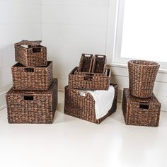 four brown wicker baskets stacked on top of each other in front of a window