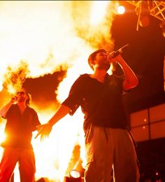 two men standing in front of a large fire