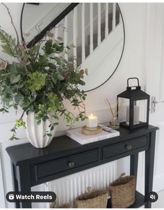 a black console table with a candle and some plants