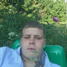 a man laying in a green lawn chair with his eyes closed and flowers growing out of his mouth