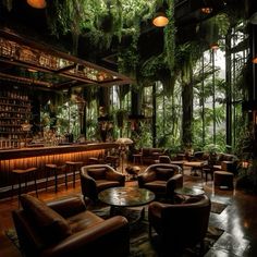 the interior of a bar with lots of greenery hanging from the ceiling and leather chairs