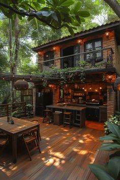 a wooden deck with an outdoor kitchen and dining table surrounded by trees in the background