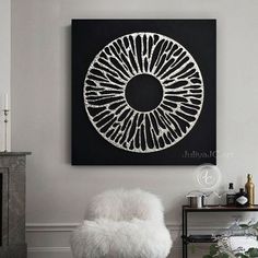 a white chair sitting in front of a black and white painting on the wall next to a fireplace