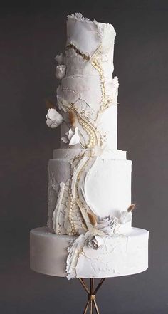 a three tiered white wedding cake with pearls