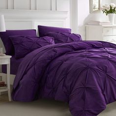 a bed with purple comforters and pillows