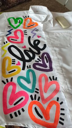 a white shirt with hearts painted on it and the words love spelled in different colors