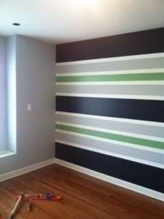 an empty room with striped walls and hard wood flooring