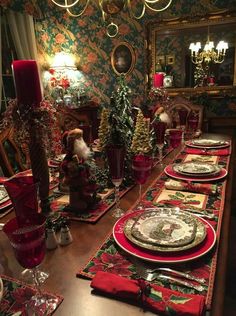 a long table is set with red and green placemats, silverware, and candles