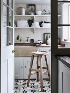 a white kitchen with black and white tile flooring, open shelving above the sink