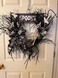 a halloween wreath on the front door decorated with skeletons and bones, black paper machs