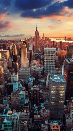 an aerial view of new york city with skyscrapers in the foreground at sunset