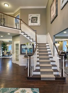 a staircase leading up to a living room and dining room in a house with hardwood floors