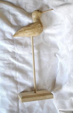 a small wooden bird on a white sheet