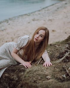 a woman laying on top of a rock near the ocean