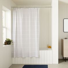 a bath room with a shower curtain and a rug on the floor in front of it