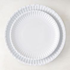 two white paper plates sitting on top of each other in front of a white background