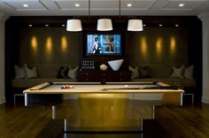 a pool table in the middle of a room with couches and lamps on either side