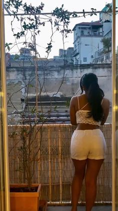 a woman in white shorts looking out the window