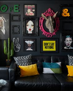 a living room filled with lots of black furniture and pictures on the wall above it