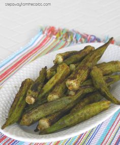 grilled okra on a white plate with colorful napkin and striped table cloth in the background