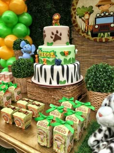 a table topped with lots of cakes next to balloons and stuffed animals on top of it