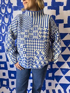 a woman standing in front of a blue and white wall with geometric designs on it