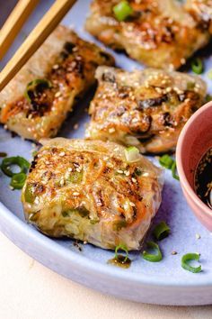 some food on a plate with chopsticks next to it and a small bowl