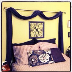 a bed that has some pillows on top of it in front of a yellow wall