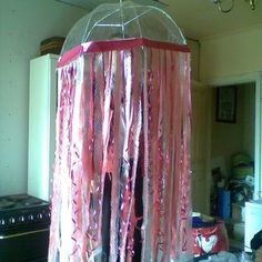 a table topped with a pink and white umbrella covered in streamers next to a stove top oven