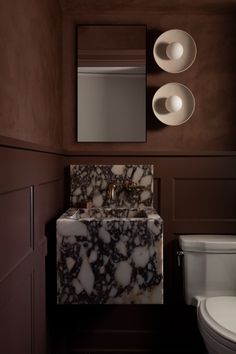 a bathroom with a sink, mirror and toilet in the corner on the wall next to it