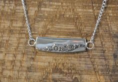 This is a handmade pendant made from a piece of antique silver-plated silverware. It has a simple floral pattern on it.  The chain and pendant together are approximately 20" long.  I have other silverware jewelry that would look very nice with this if you like this style. Here are a few options: Vertical necklace -- https://www.etsy.com/listing/738111804/antique-silver-plate-pendant-with?ref=shop_home_active_29&frs=1 Horizontal necklace -- https://www.etsy.com/listing/737892668/antique-silver-plate-pendant-with?ref=shop_home_active_37&frs=1 Daffodil necklace -- https://www.etsy.com/listing/737852030/antique-silver-plate-pendant-with?ref=shop_home_active_46&frs=1 Thank you for considering my handmade items! Please note that since this is from antique silver plate, it may have minor imperfec Daffodil Necklace, Simple Floral Pattern, Simple Motif, Jewelry Bar, Chain And Pendant, Silverware Jewelry, Silver Bar Necklace, Garnet And Gold, Silver Bar