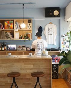 two stools are in front of a counter with t - shirts hanging on it