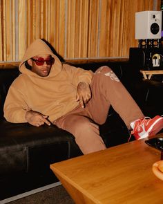 a man sitting on top of a couch in a living room next to a wooden table