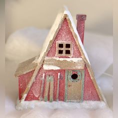 a small red house with snow on the roof and windows is sitting in front of a white background