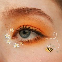 a woman's eye with yellow and white flowers painted on her eyeshade